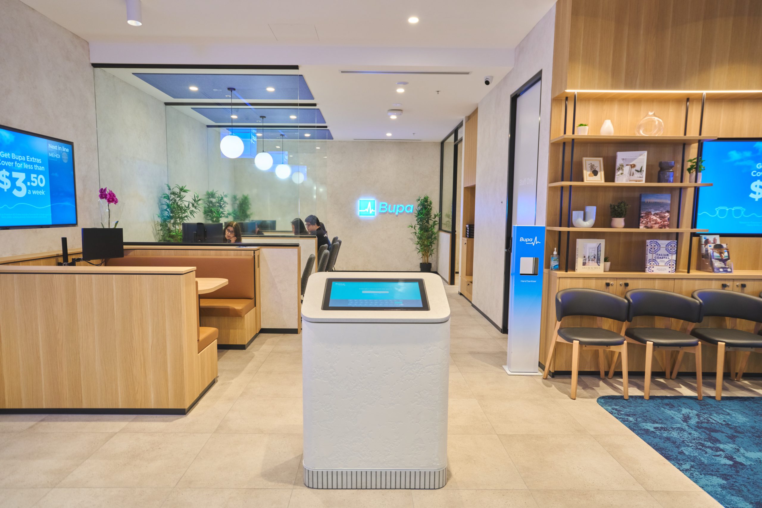 2 Elegant and Reliable Interactive Kiosk Bupa branch interior with wall screens, an interactive kiosk and waiting area seating