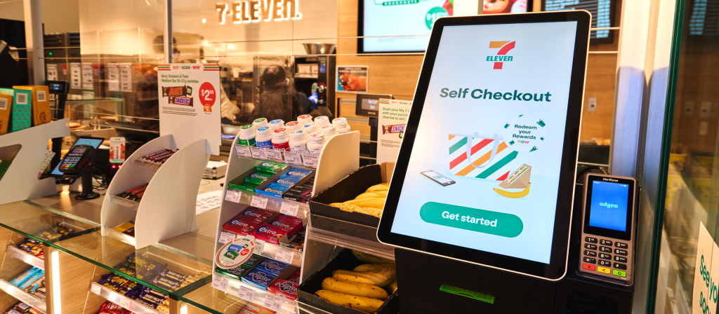 Self-checkout touch screen kiosk in a 7-Eleven convenience store showing in-store retail media